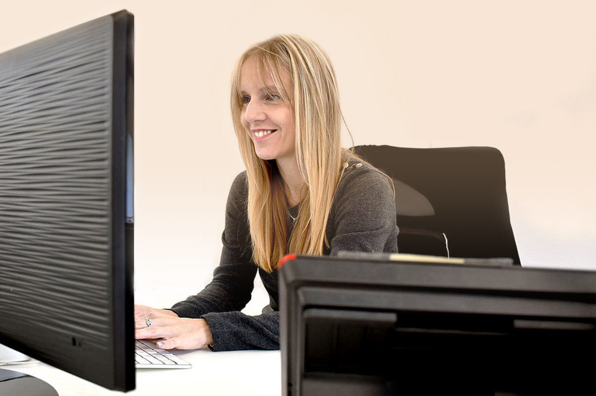 A woman smiling working on her desktop computer