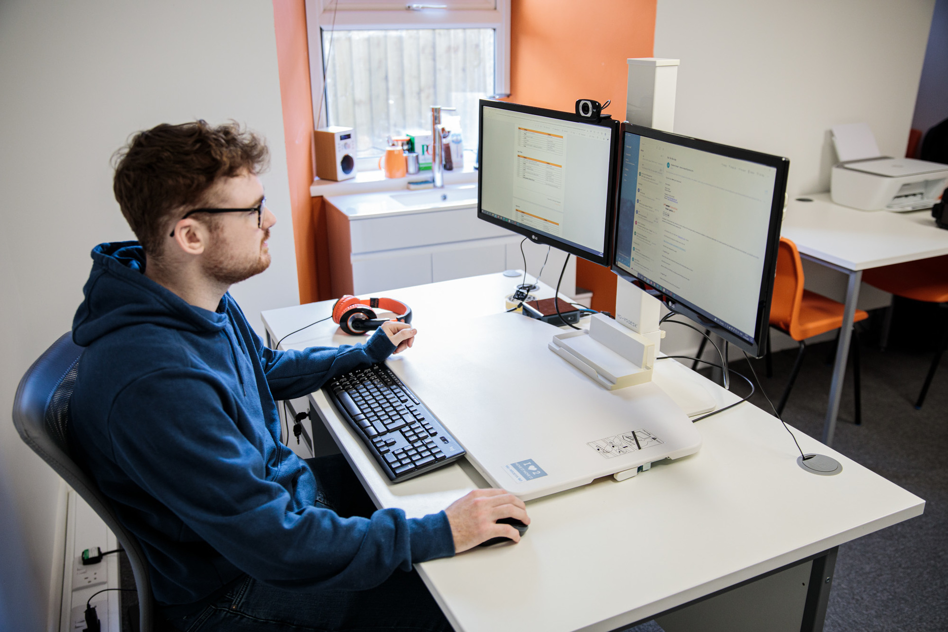 A man sat at his desk concentrating on his desktop computer
